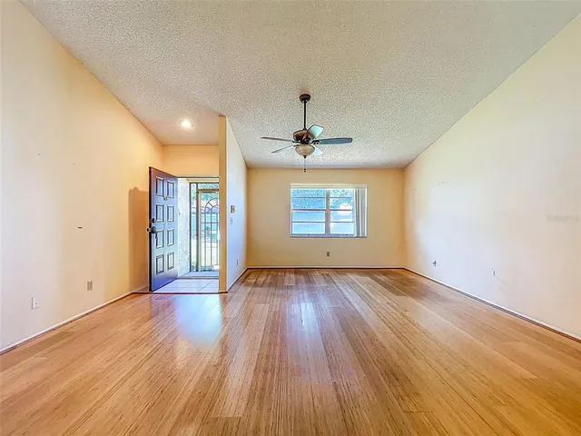 an empty room with wooden floor chandelier and windows