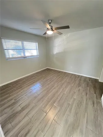an empty room with wooden floor fan and windows