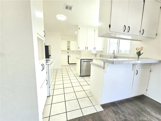 a kitchen with stainless steel appliances a sink a stove a refrigerator cabinets and a window