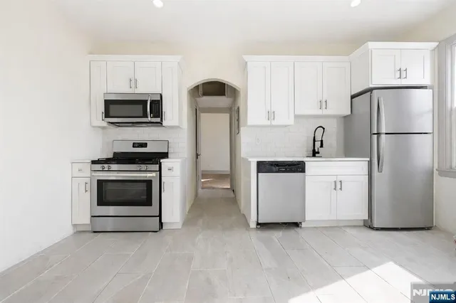 a kitchen with white cabinets and stainless steel appliances
