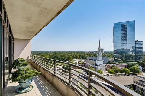 a view of balcony with a couple of cars parked in front of a house