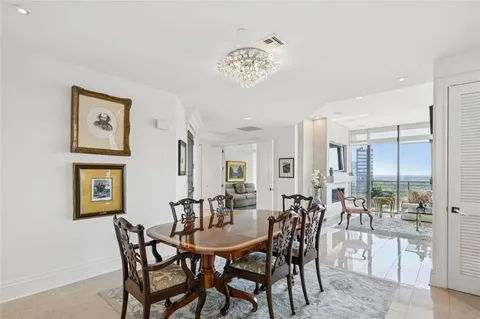 a view of a dining room and livingroom with furniture a rug a painting and a chandelier