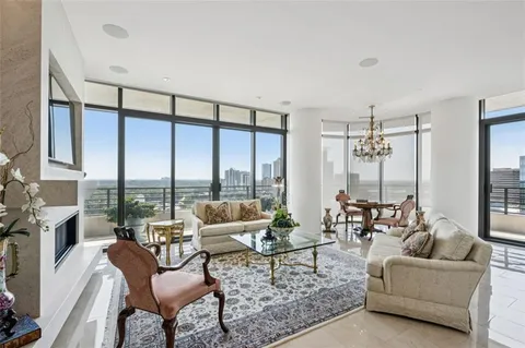 a living room with furniture large windows and a chandelier