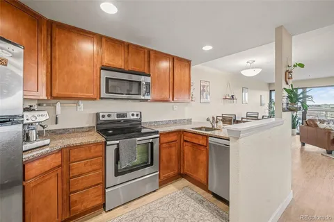 a kitchen with stainless steel appliances granite countertop wooden cabinets a stove a sink and a microwave