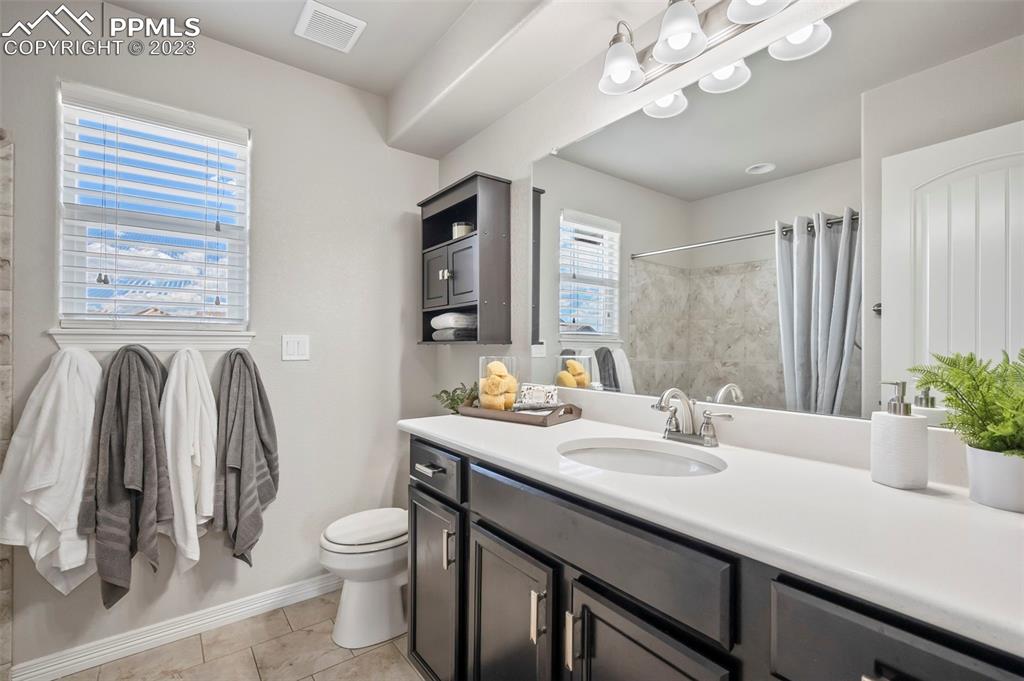 13232 Park Meadows Drive Peyton, CO 80831 - Photo 22 of 23 a bathroom with a granite countertop sink a toilet and a mirror