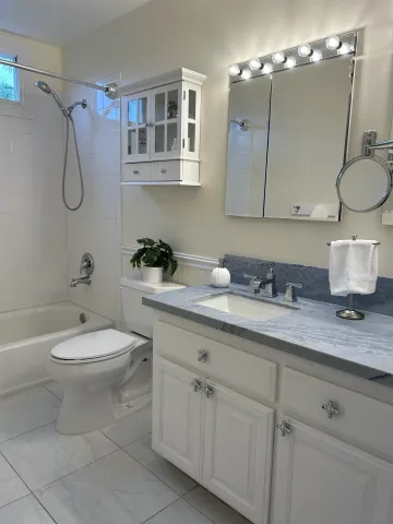 a bathroom with a granite countertop sink mirror vanity and toilet