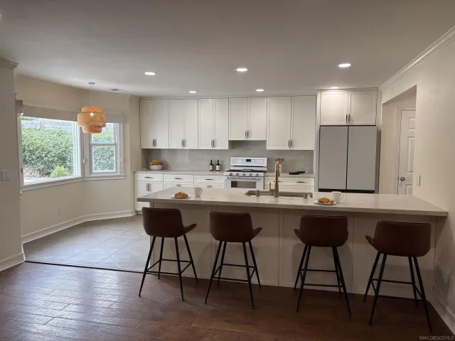 a kitchen with stainless steel appliances granite countertop a sink a stove a refrigerator and island with wooden floor