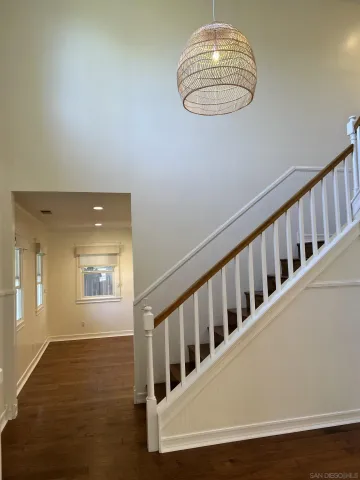 a view of an empty room with wooden floor and windows