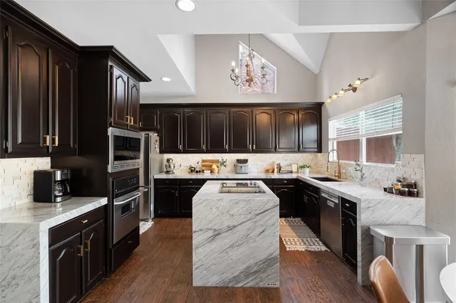 a kitchen with stainless steel appliances granite countertop a stove refrigerator and cabinets
