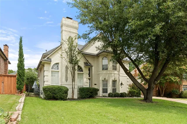 a view of a white house next to a yard with big trees