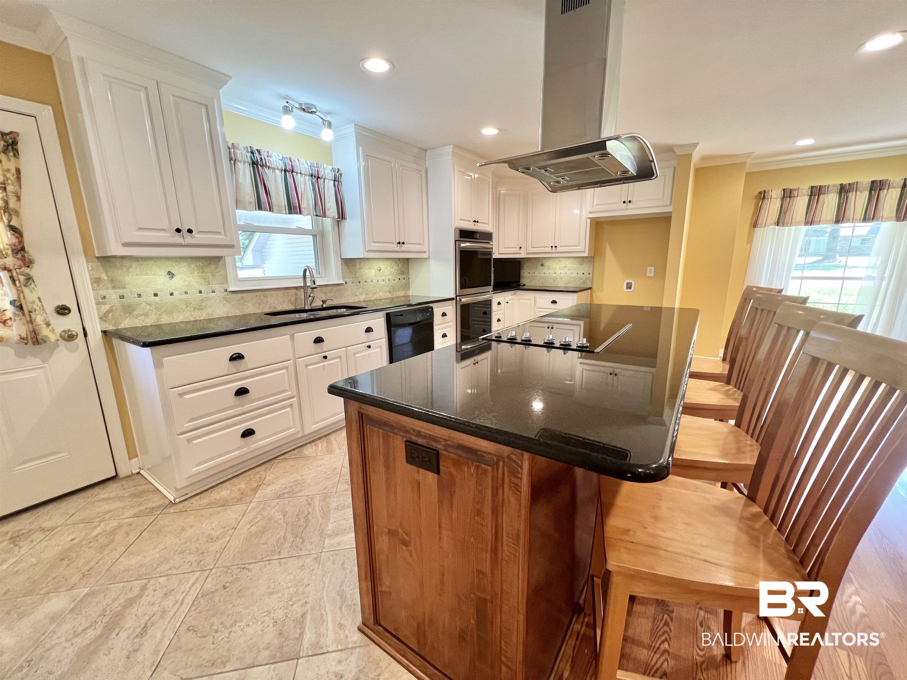2691 Appleton Road Brewton, AL 36426 - Photo 11 of 60 Kitchen featuring ornamental molding, island exhaust hood, a center island, white cabinetry, and a kitchen breakfast bar