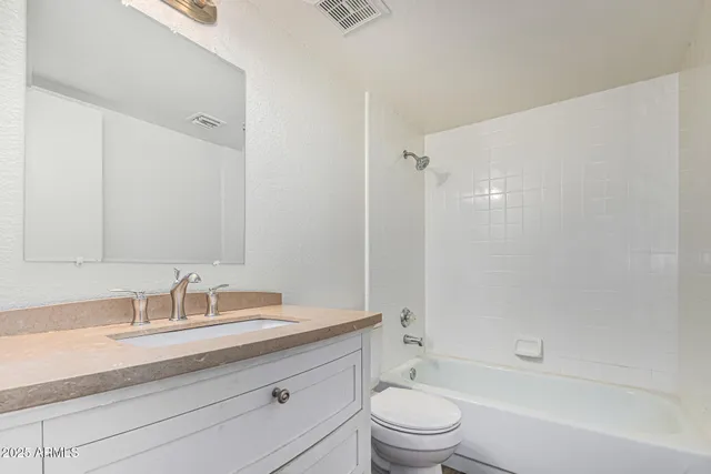 a bathroom with a granite countertop sink a toilet and shower