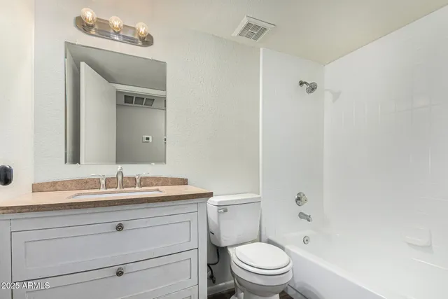 a bathroom with a granite countertop sink a toilet and a mirror