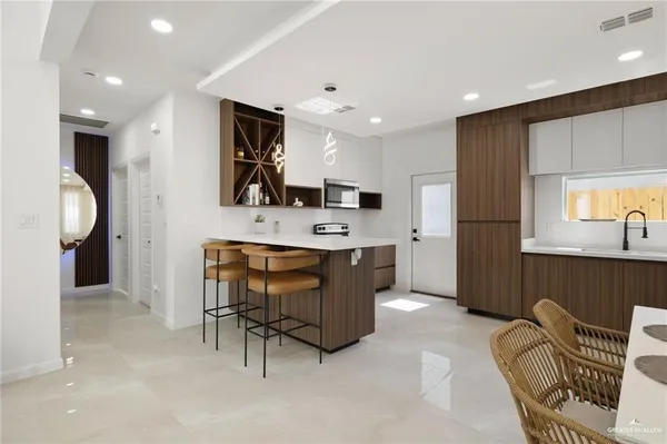 a large kitchen with stainless steel appliances kitchen island granite countertop a refrigerator and a sink