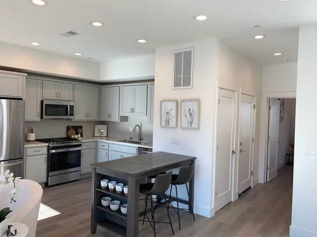 a kitchen with stainless steel appliances granite countertop a kitchen island hardwood floor and a sink