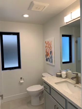 a bathroom with a granite countertop sink mirror and toilet