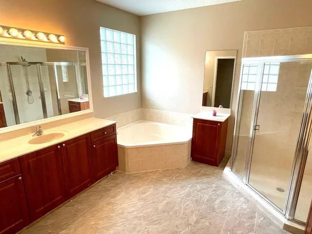 a spacious bathroom with a tub sink and mirror