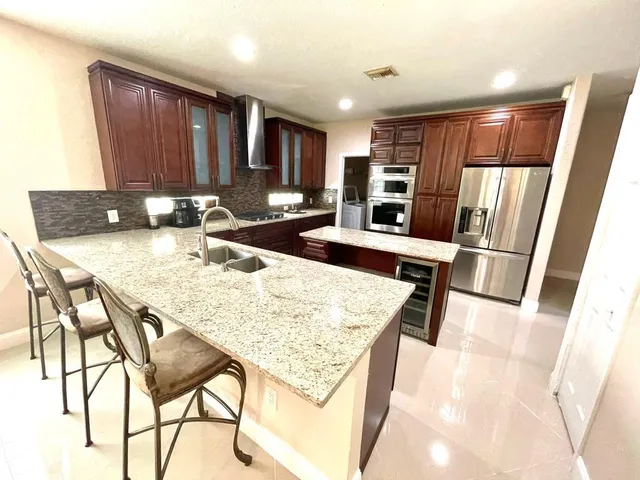 a kitchen with stainless steel appliances granite countertop table chairs and a refrigerator