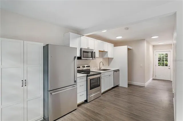 a kitchen with a sink stainless steel appliances and wooden floor