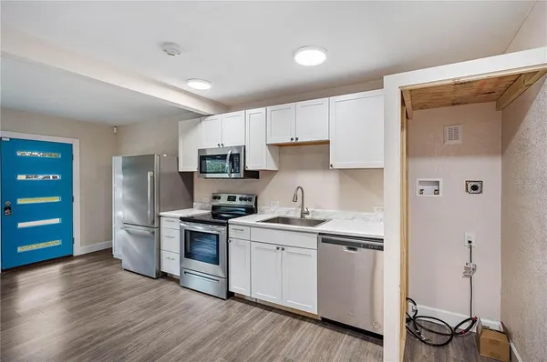 a kitchen with stainless steel appliances a stove top oven a sink dishwasher and a refrigerator