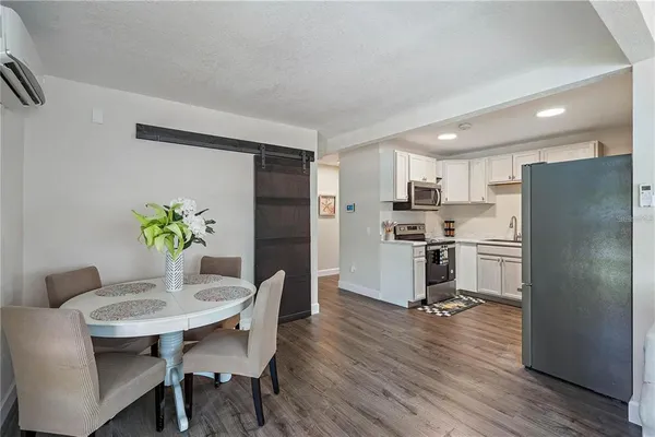 a kitchen with stainless steel appliances a refrigerator a stove a dining table and chairs with wooden floor