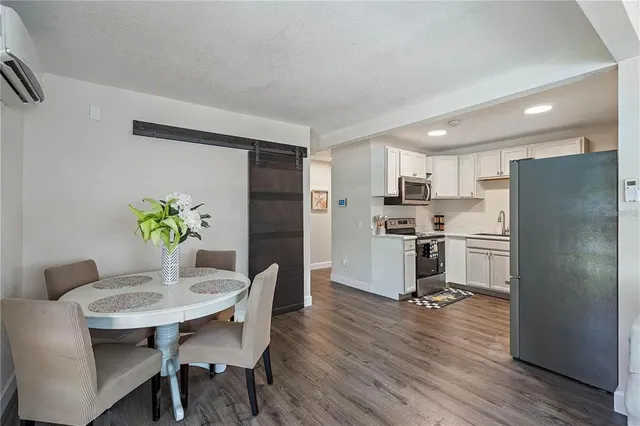 a kitchen with stainless steel appliances a refrigerator a stove a dining table and chairs with wooden floor