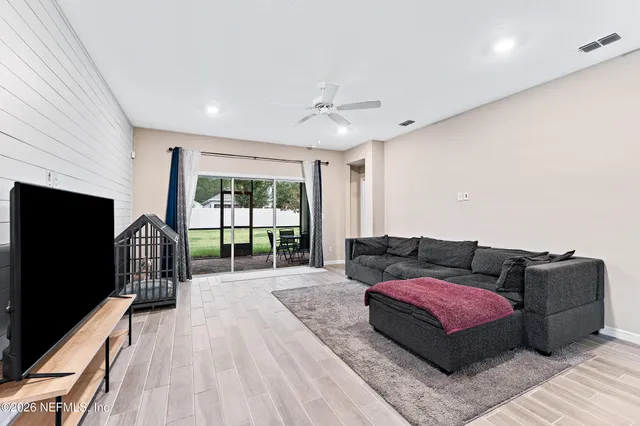a living room with furniture a flat screen tv and a floor to ceiling window
