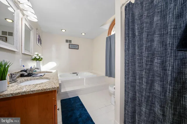 a bathroom with a granite countertop sink a toilet and shower