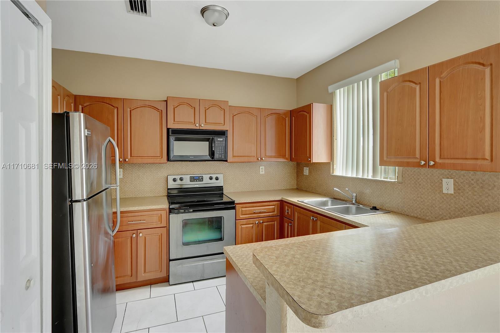 2874 Southeast 15th Road, Unit 52 Homestead, FL 33035 - Photo 7 of 16 a kitchen with granite countertop a stove sink and refrigerator