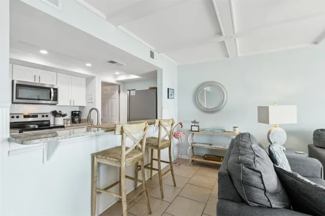 a living room with furniture a mirror and a view of kitchen