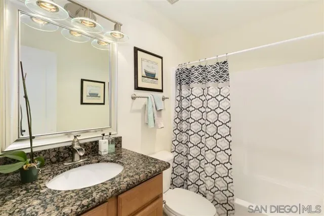 a bathroom with a granite countertop sink toilet and shower