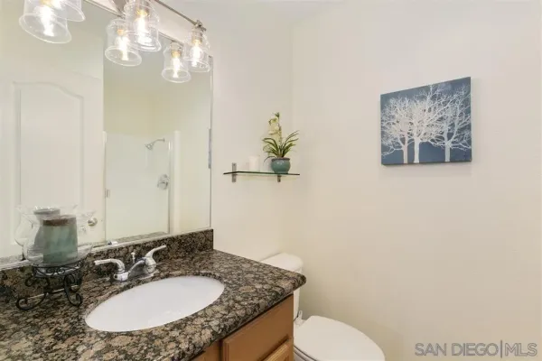 a bathroom with a granite countertop sink mirror and toilet