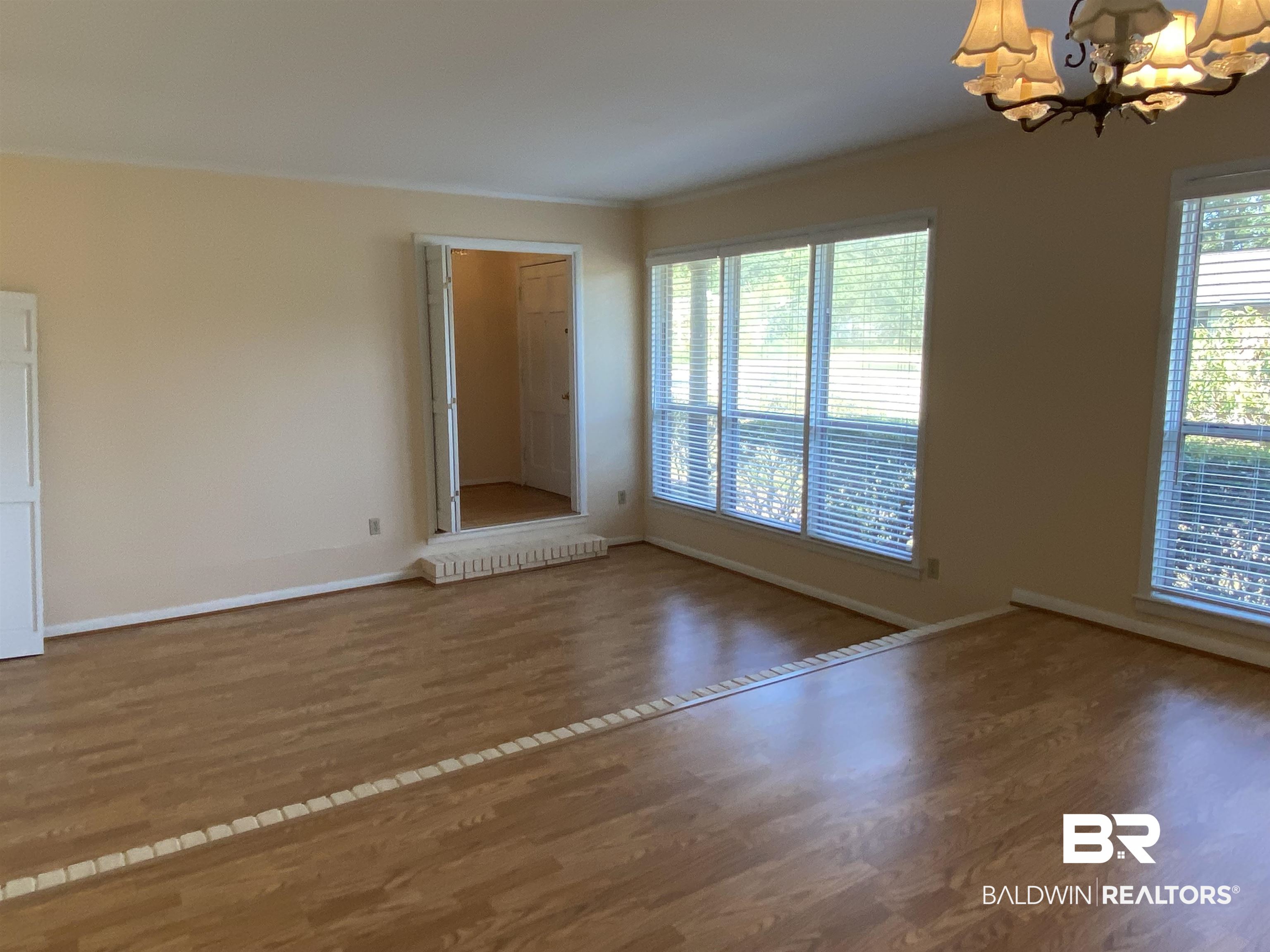 106 Terry Drive Brewton, AL 36426 - Photo 4 of 25 Room featuring a chandelier, wood finished floors, healthy amount of natural light, and crown molding with step down to the living room.