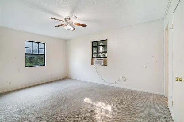 an empty room with wooden floor chandelier fan and windows