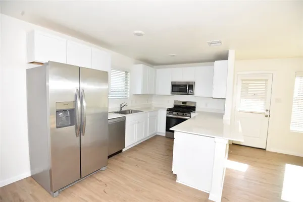 a kitchen with cabinets stainless steel appliances and wooden floor