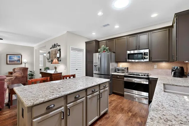 a kitchen with stainless steel appliances granite countertop a stove refrigerator and cabinets