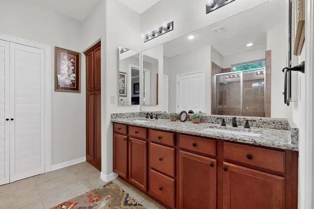 a bathroom with a granite countertop double vanity sink and a mirror