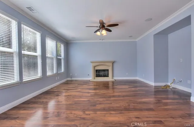 a view of an empty room with a window and wooden floor