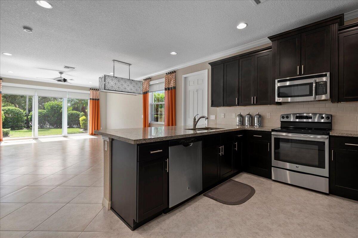 692 Southwest Glen Crest Way Stuart, FL 34997 - Photo 5 of 37 a kitchen with stainless steel appliances granite countertop a stove a sink and a microwave