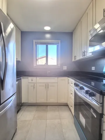 a kitchen with granite countertop white cabinets and white appliances