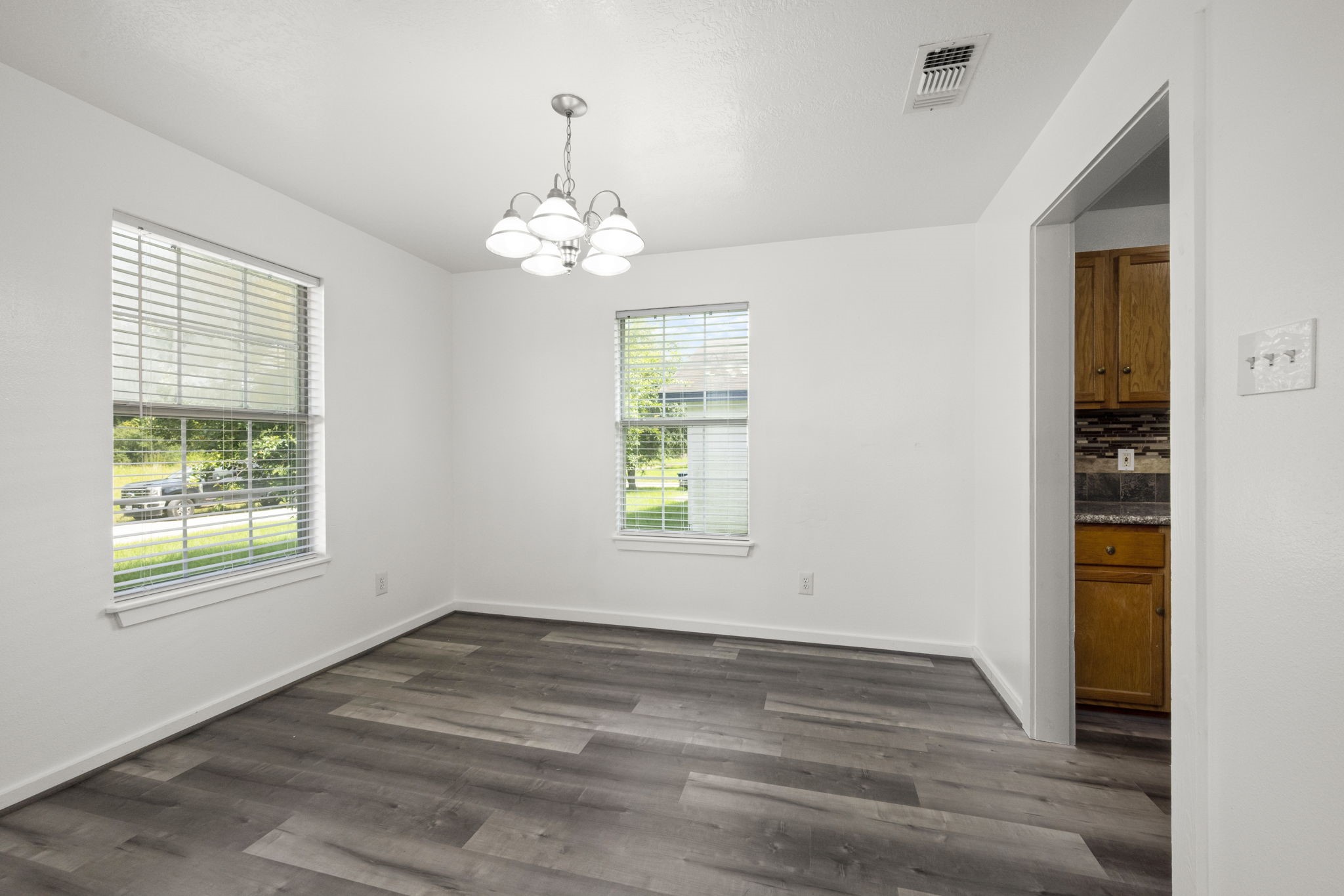 1935 1st Street Hempstead, TX 77445 - Photo 17 of 29 an empty room with wooden floor chandelier and windows