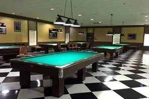 a room with pool table kitchen view and a fireplace