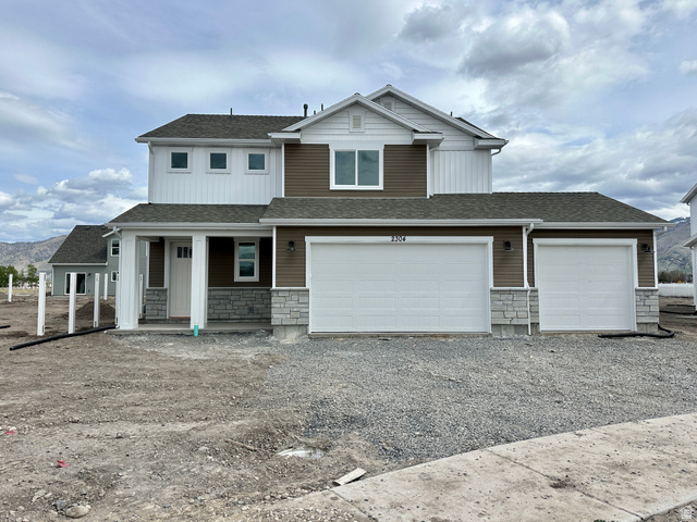 2304 South 1050 West, Unit 102 Logan, UT 84321 - Photo 1 of 1 View of front of property with stone siding, a shingled roof, a porch, and gravel driveway