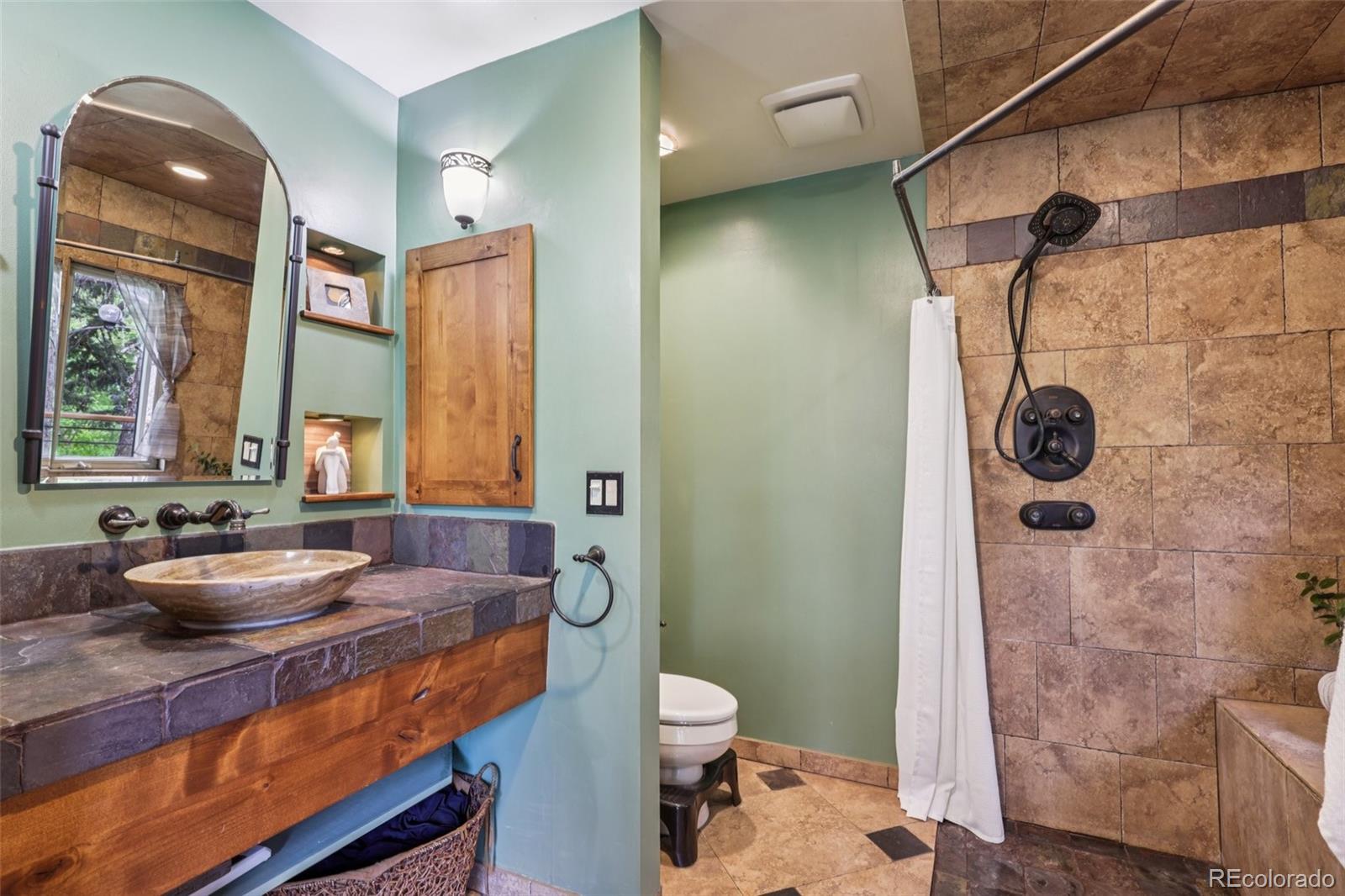 20033 Silver Ranch Road Conifer, CO 80433 - Photo 18 of 43 a bathroom with a granite countertop sink a toilet a mirror and shower