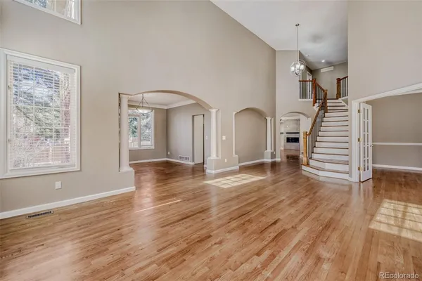 a view of empty room with wooden floor and fan