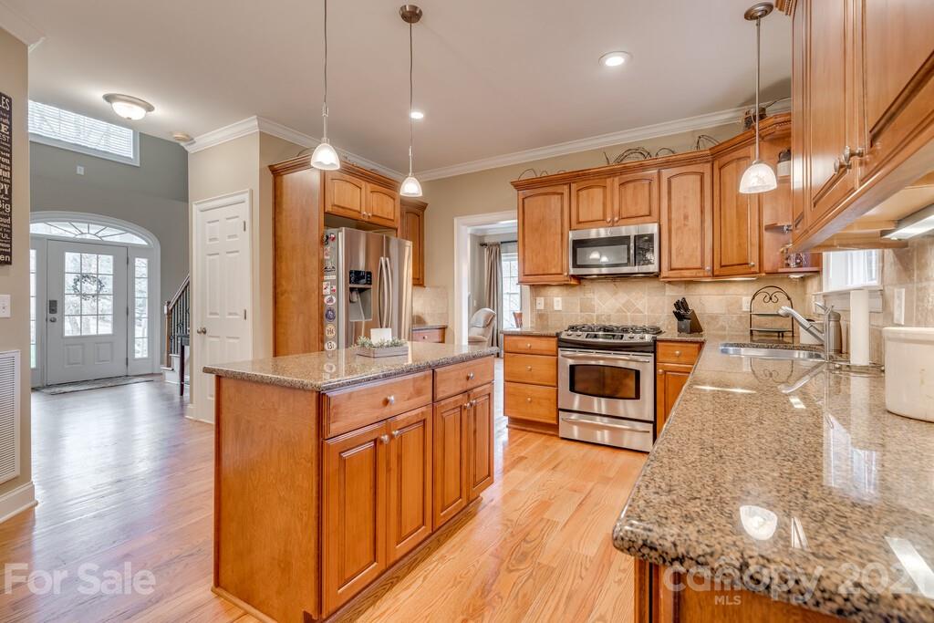11155 Turtle Bay Court Tega Cay, SC 29708 - Photo 8 of 36 a kitchen with stainless steel appliances kitchen island granite countertop a stove top oven a sink a dining table and chairs with wooden floor