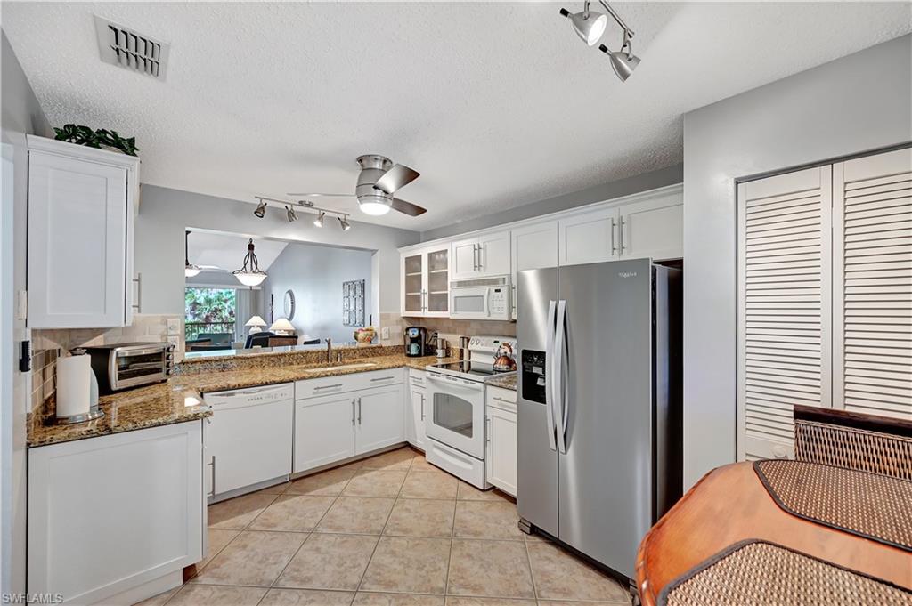 784 Landover Circle, Unit 203 Naples, FL 34104 - Photo 3 of 16 a kitchen with white cabinets and stainless steel appliances