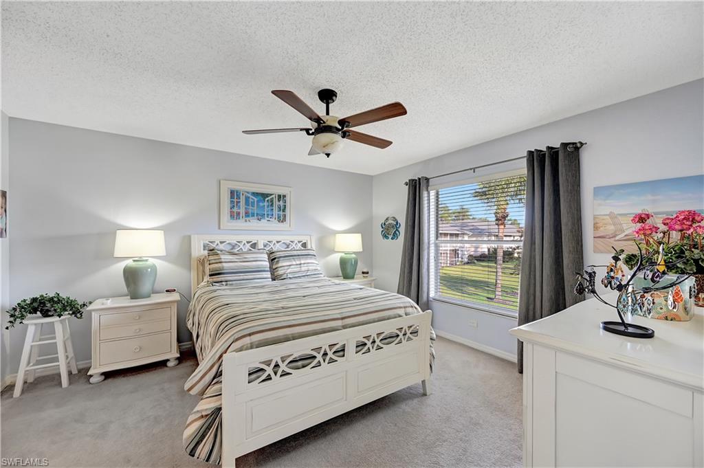 784 Landover Circle, Unit 203 Naples, FL 34104 - Photo 6 of 16 a bedroom with a bed chandelier and a window