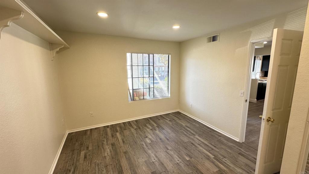 13062 Wimberly Square San Diego, CA 92128 - Photo 7 of 14 a view of an empty room with wooden floor and a window