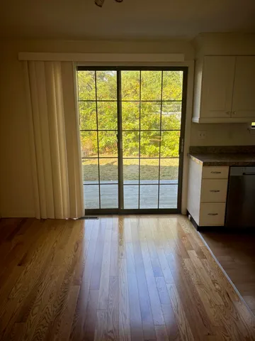 an empty room with wooden floor and windows with curtains
